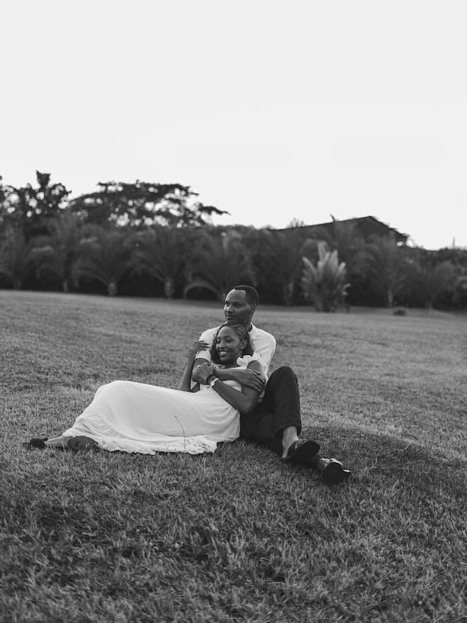 Khalim holding Celine as they sit together on the grass